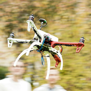 Eine Drohne fliegt über die Köpfe von jungen Forschern.